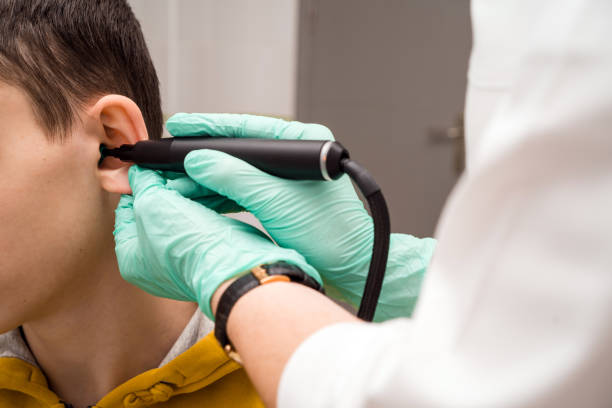 Preventive inspection of a teenage boy in a medical facility. Otorhinolaryngologist doctor pediatrician. Inspection of the sinuses of the ear with the reflector of the forehead and the nasal mirror